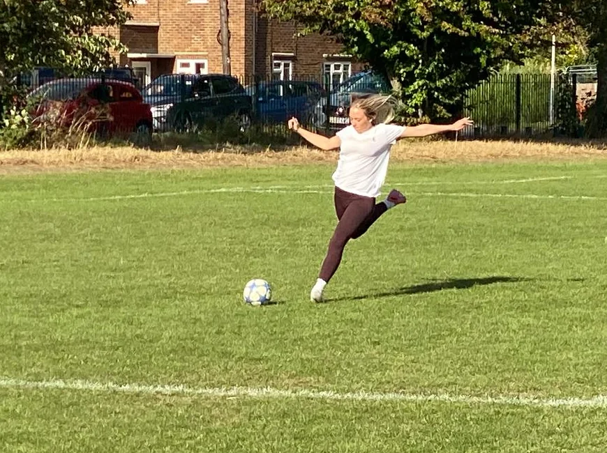 Alexa mid-kick on a football pitch